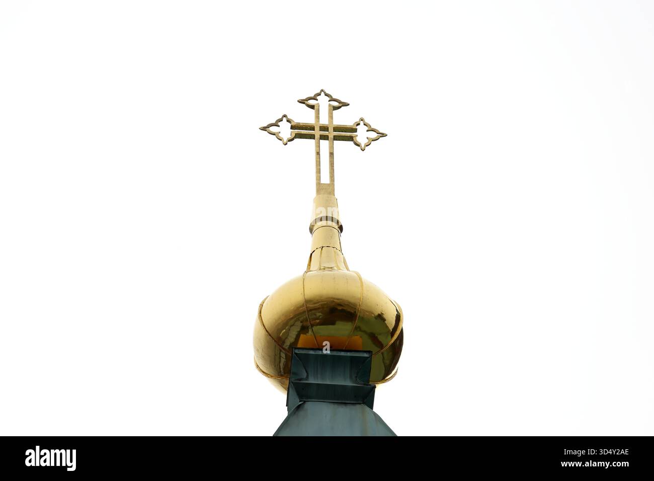 Orthodoxes Kreuz und goldene Zwiebelfinial auf einem Kupferturm in der Uspenski Kathedrale in Helsinki, Finnland, fotografiert von unten vor einem weißen Himmel. Stockfoto