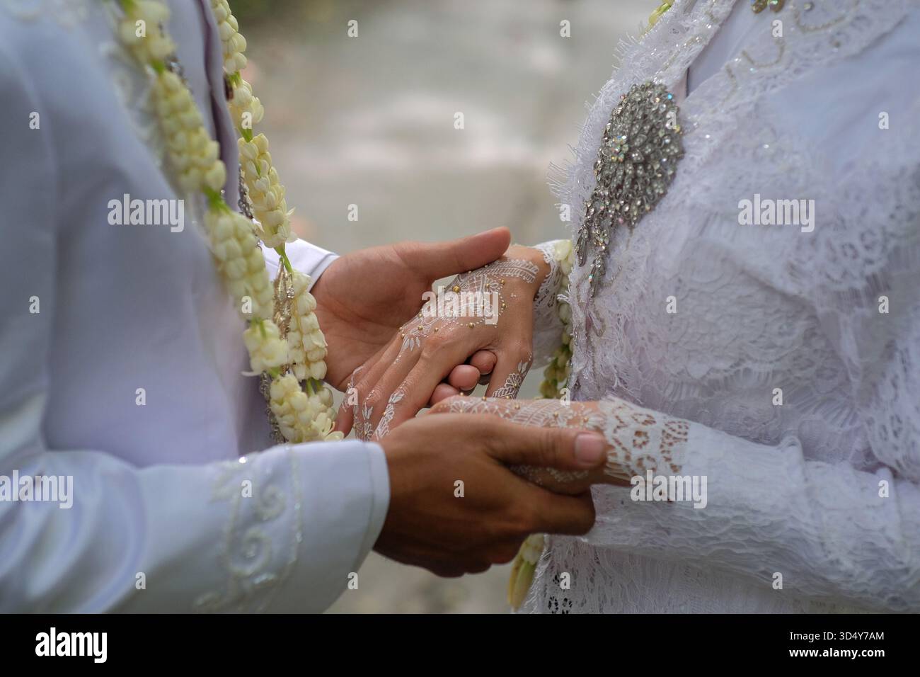 Nahaufnahme eines Brautpaares, das sich liebevoll hält. Beide waren in weißen, traditionellen Hochzeitskleidern gekleidet. Stockfoto