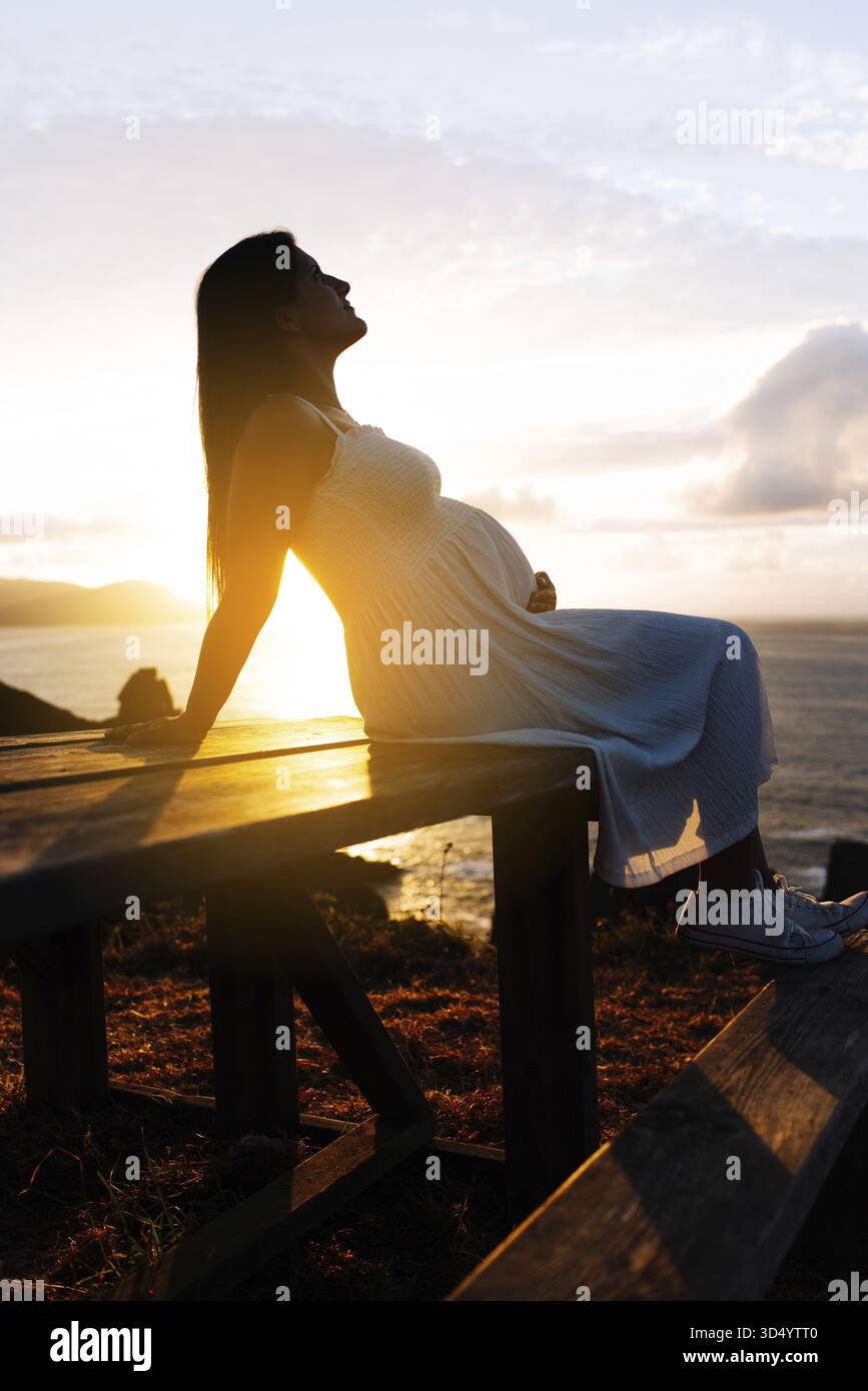 Porträt einer schwangeren Frau gegen eine ozeanische Landschaft bei Sonnenuntergang in Galicien, Spanien Stockfoto