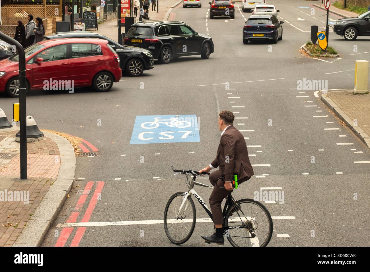 LONDON - 8. OKTOBER 2025: Geschäftsmann radelt durch die CST7 Bike Box auf der Balham High Road, South London Stockfoto