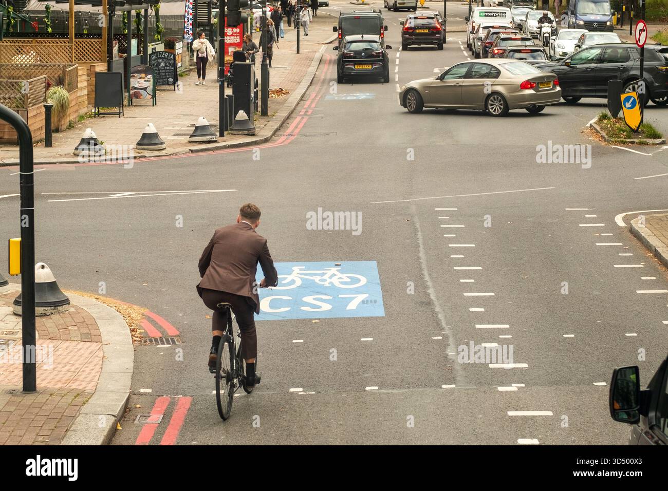 LONDON - 8. OKTOBER 2025: Geschäftsmann radelt durch die CST7 Bike Box auf der Balham High Road, South London Stockfoto