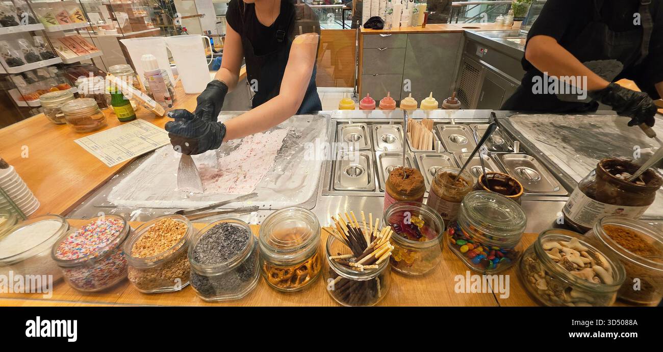 Berlin, Deutschland - 19. September 2025: Mitarbeiter der Eisdiele bereitet Dessert mit verschiedenen Toppings zu. - Smartphone-aufgenommenes Stockfoto