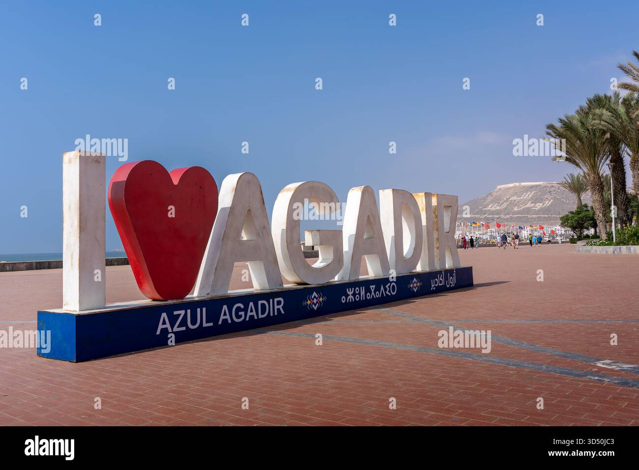 Das I Love Agadir-Schild mit dem Agadir Oufella Kasbah auf dem Hügel in der Ferne, an der Promenade Stockfoto
