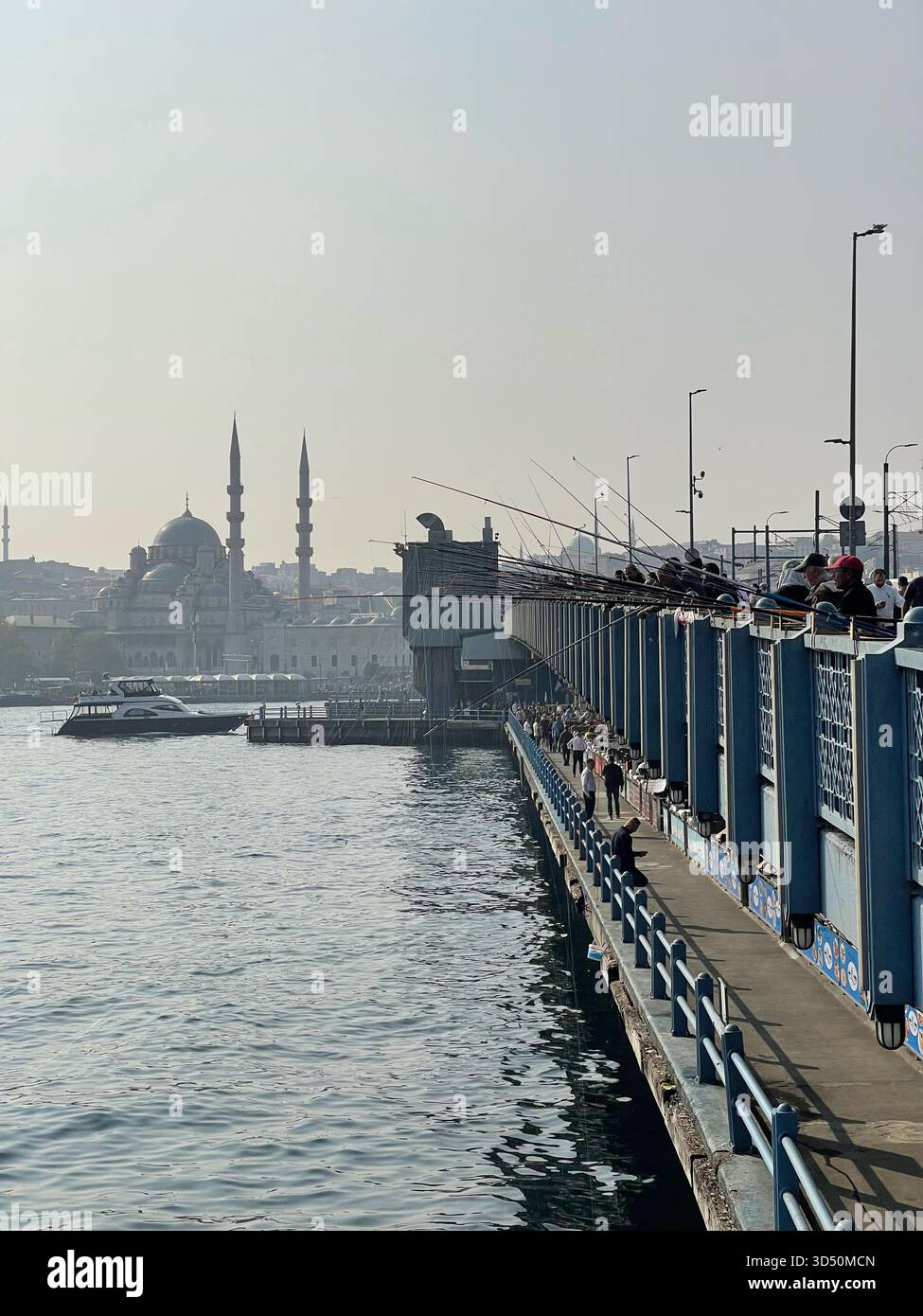 Galata-Brücke in Istanbul, Türkiye, voller Fußgänger und Fischer, mit osmanischen Moscheen, die über das Goldene Horn sichtbar sind Stockfoto