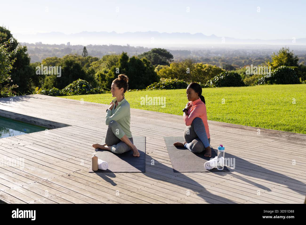 Verschiedene schwangere Freunde dehnen und auf dem Pooldeck sitzen, mit Yoga-Matten und -Flaschen Stockfoto