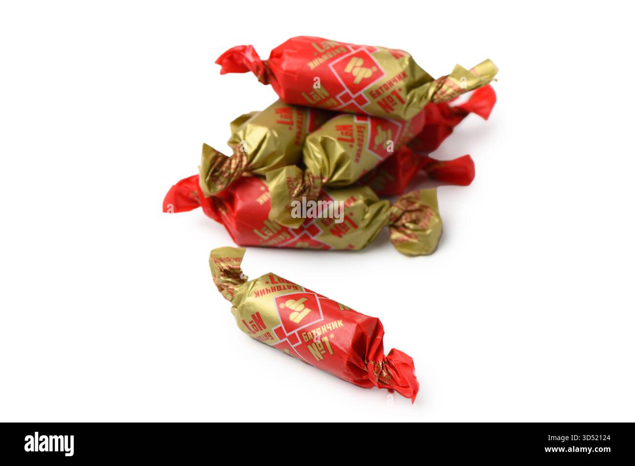 Tbilisi, Georgia 11.09.2025 Nahaufnahme des klassischen Batonchiki Rot Front in Wrapper auf weißem Hintergrund. Goldene Folie und Schokoladenglasur betonen Nostalgie Stockfoto