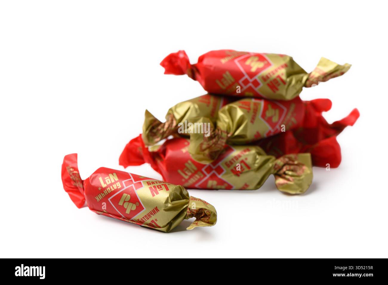 Tbilisi, Georgien 11.09.2025 Nahaufnahme von Rot Front Batonchiki mit Schokoladenglasur und goldener Folie auf weißem Hintergrund. Traditionelles Design und Appetit Stockfoto