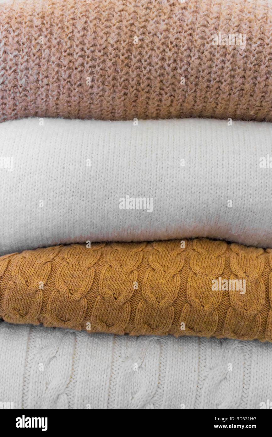 Nahaufnahme warmer Strickpullover in Pastellfarben und Beige, ordentlich gestapelt. Stockfoto
