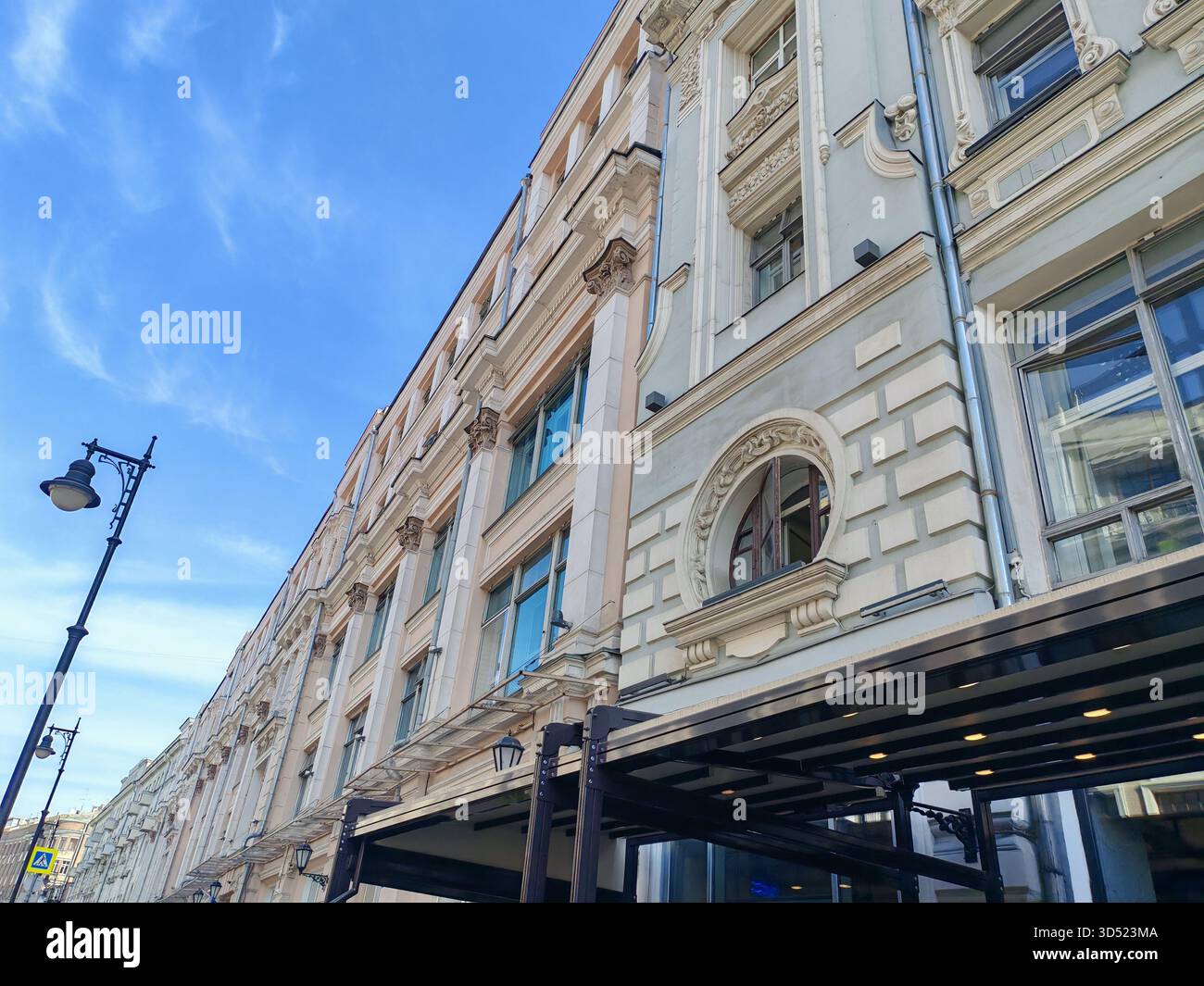 Großes mehrstöckiges Gebäude mit klassischer Fassade mit Bogenfenstern und modernen Verkaufsflächen im Erdgeschoss. Die Mischung aus traditionellem Stockfoto