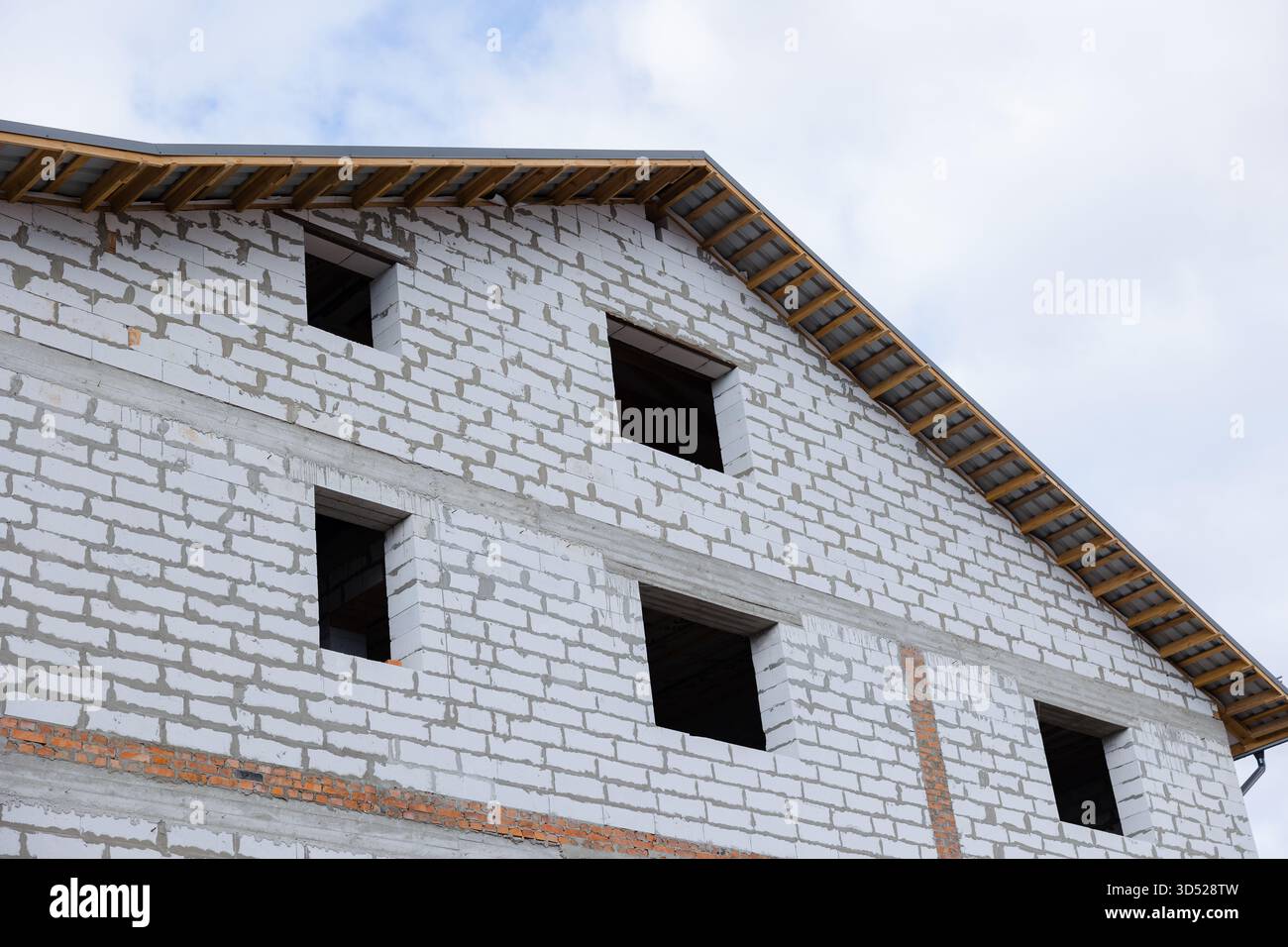 In einem Baubereich steht ein unvollständiges Gebäude hoch, mit freiliegenden Wänden und Öffnungen, die auf den letzten Schliff warten. Stockfoto