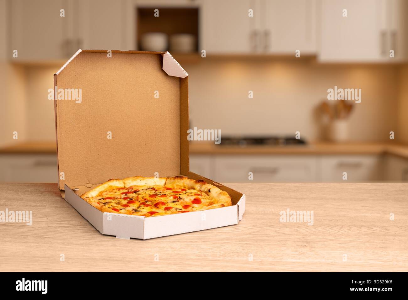 Frisch gebackene Pizza im offenen Karton auf hölzernem Küchentisch, warmes Licht und weicher Hintergrund ideal für Essenslieferung und Restaurantwerbung Stockfoto