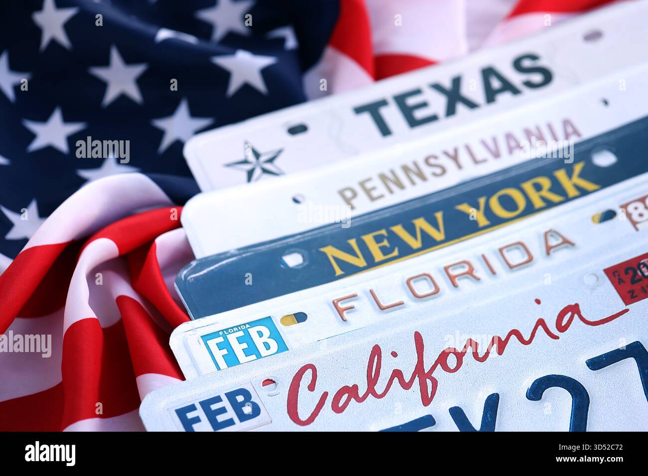 Alte US-Autokennzeichen mit verschiedenen Namen auf der US-Flagge. Konzept des Fahrens in den USA. Erreichen einer Fahrzeugregistrierung Stockfoto