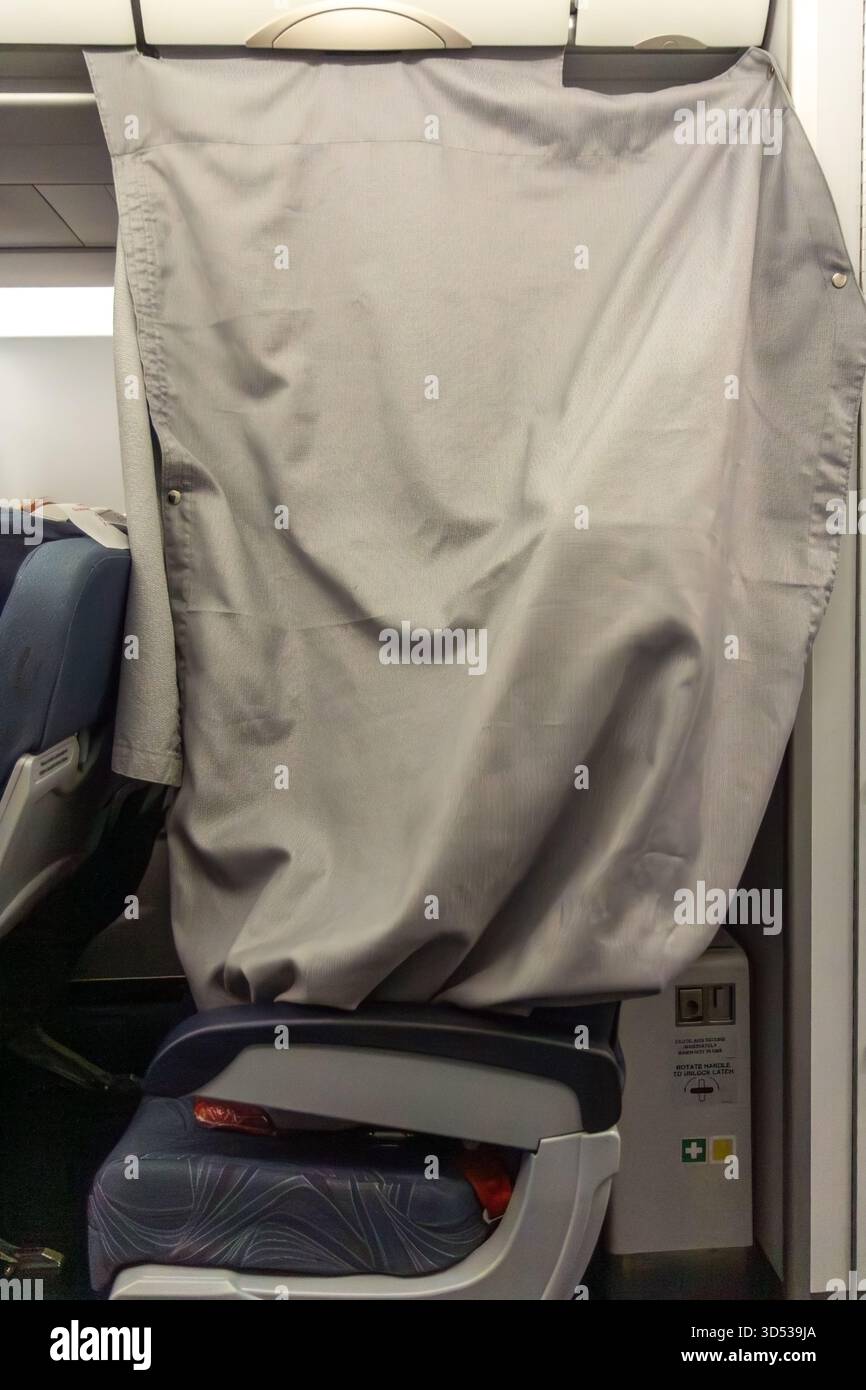 Eine Reihe von Sitzplätzen in einem Nachtflugzeug ist mit einem Stoffvorhang bedeckt, was Privatsphäre und eine ruhige Atmosphäre schafft. Private Einrichtungen für die Kabinenbesatzung. Stockfoto