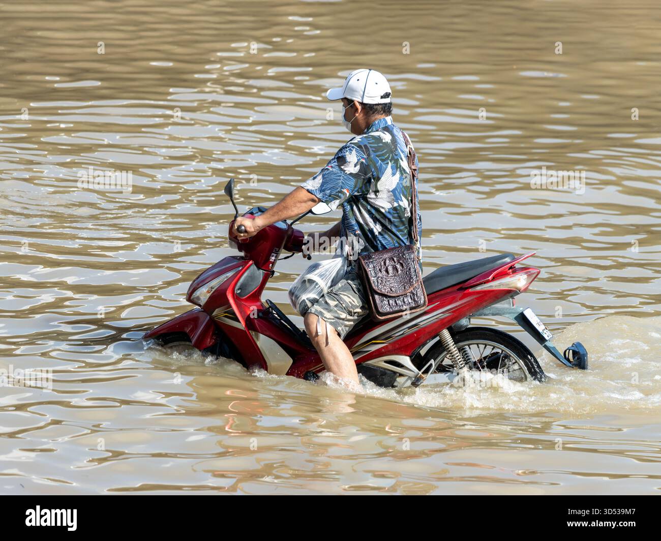 Ein Motorrad fährt auf einer überfluteten Straße, Thailand Stockfoto