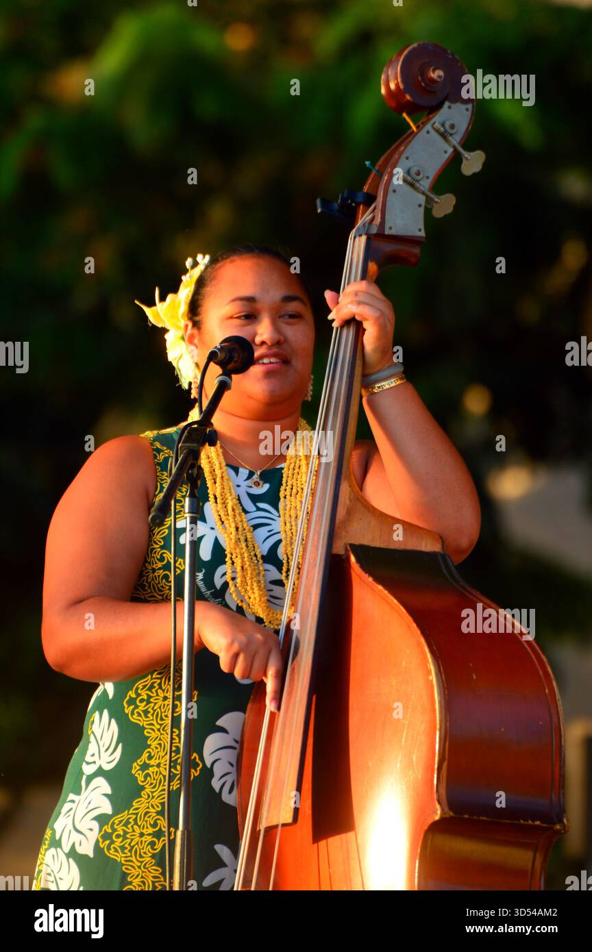 Waikiki Beach, HI, USA 1. August 2014 Eine junge Frau in traditioneller hawaiianischer Kleidung spielt den Bass bei einer Hula-Show in Waikiki Beach, Hawaii Stockfoto