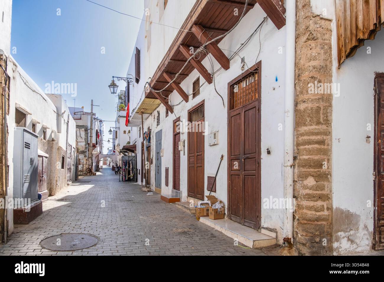 Rabat, Marokko – Eine ruhige, enge Gasse in der historischen Medina von Rabat, gesäumt von weiß getünchten Gebäuden, traditionellen Holztüren und dekorativen Strassen Stockfoto