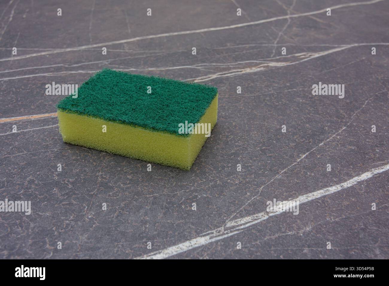 Ein gelber Reinigungsschwamm auf einer Marmorplatte Stockfoto