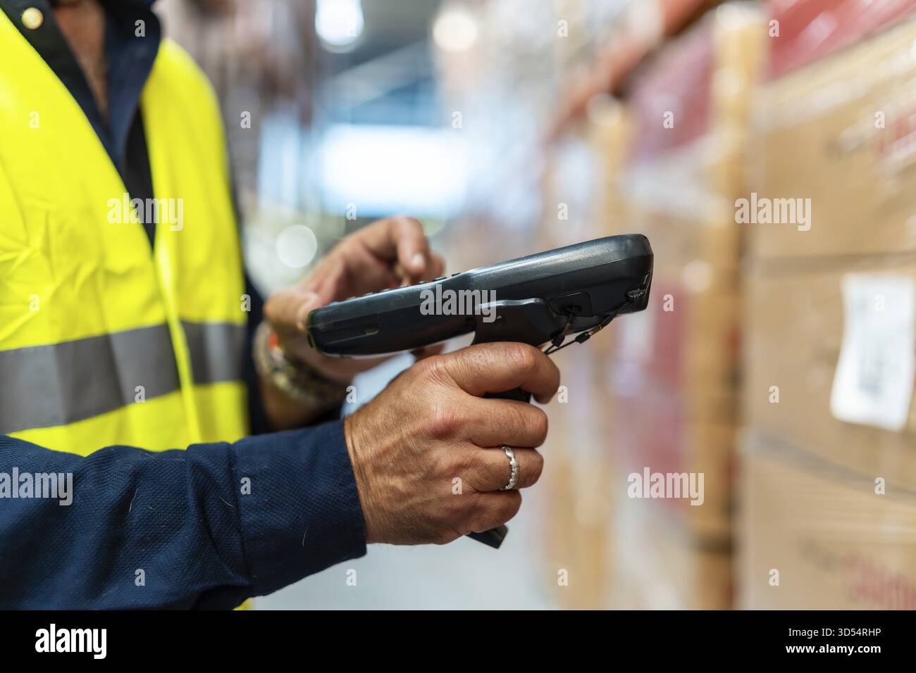Lagerarbeiter in gut sichtbarer Weste und blauem, einheitlichem Scannen von Barcodes auf Kartons mit Handscanner, Aktualisierung des Bestands und Nachverfolgung des Bestands in A Stockfoto
