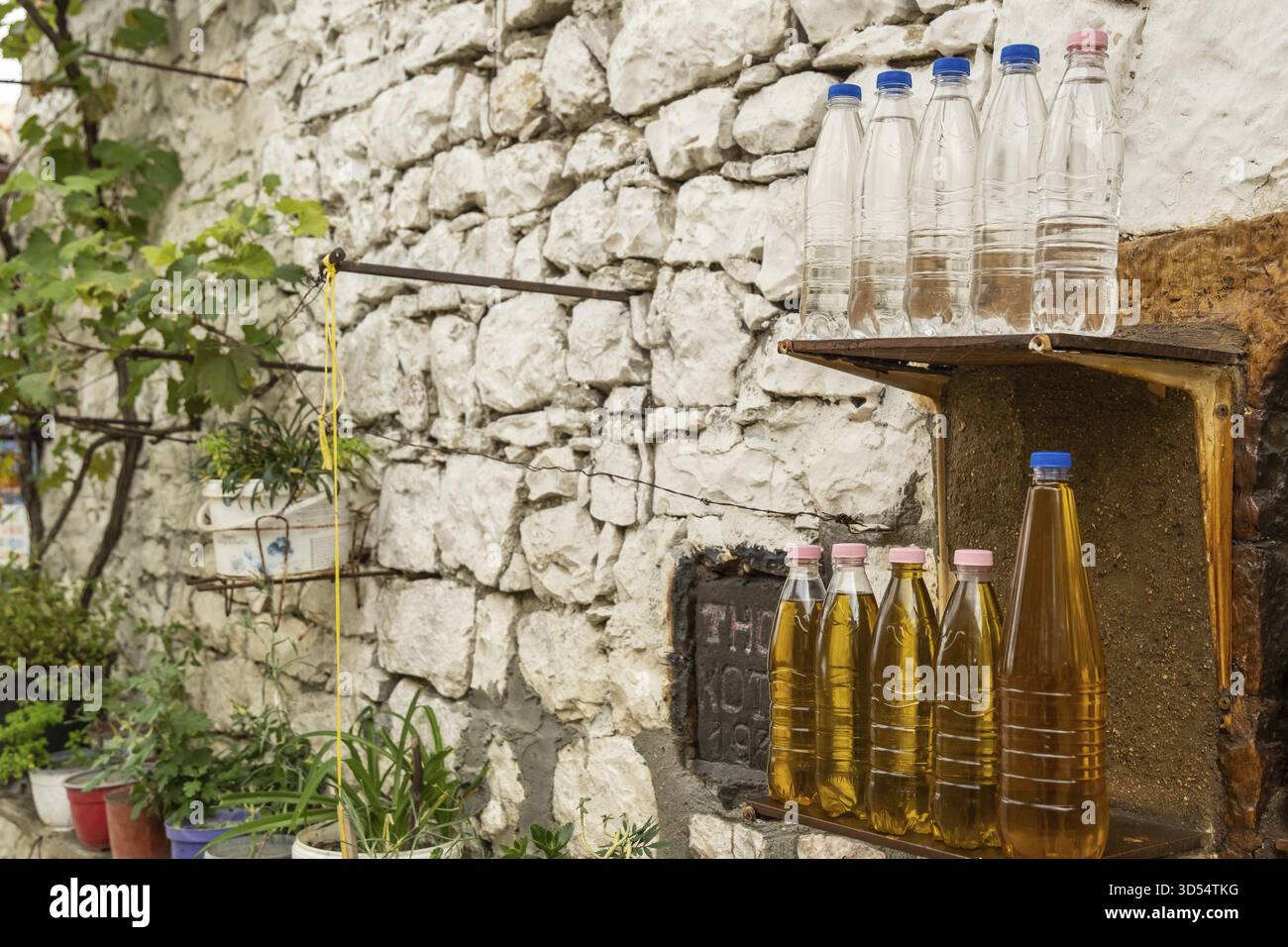 Hausfassade mit Naturstein und Plastikflaschen mit Öl und Raki, Berat, Bezirk Berat, Albanien Stockfoto