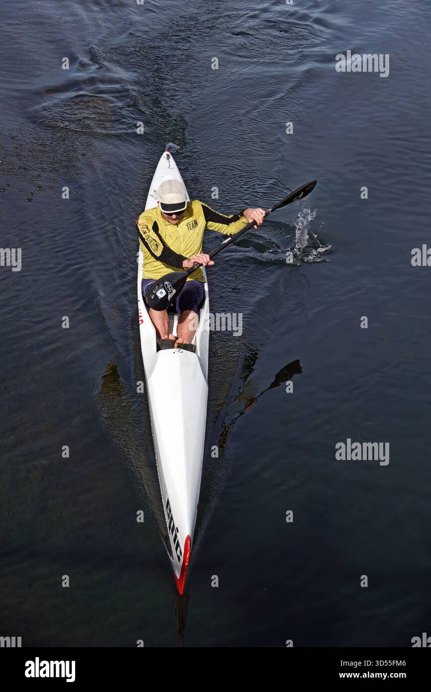 Ein Mann im Rennkayak paddelt auf dem flachen Wasser des Deschutes River im Old Mill Shopping Area von Bend, Oregon. Stockfoto