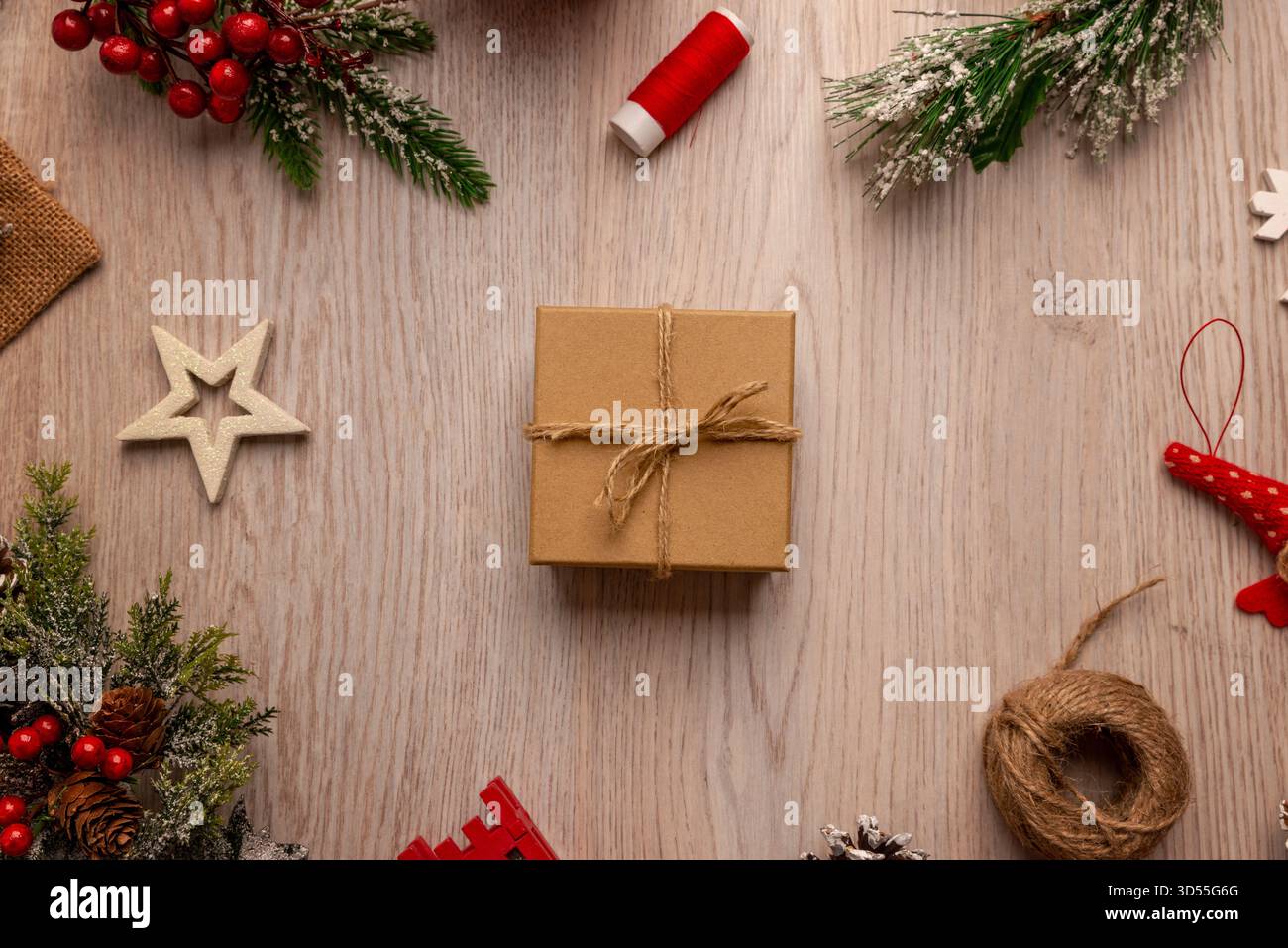 Geschenkbox mit Garn auf Holztisch, umgeben von festlichen Elementen, ideal für Verpackungskonzepte, Branding für kleine Unternehmen und handgefertigte Produkte Stockfoto