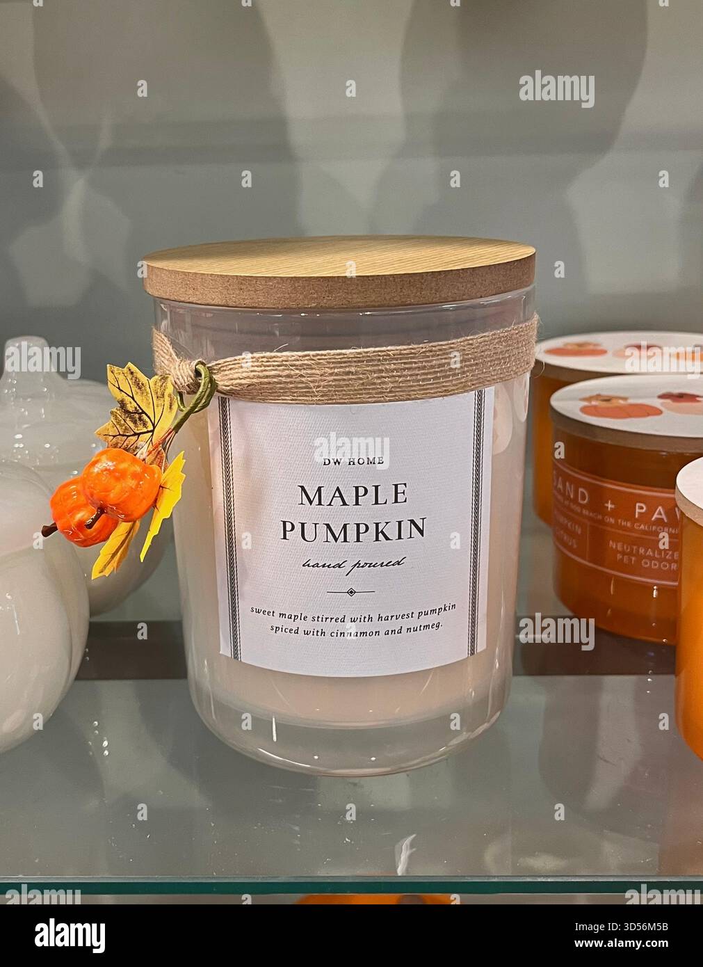 Nahaufnahme einer Kerze mit Ahornkürbis-Duft in einem Ladenregal in Hull, England. Die Kerze ist mit saisonalem Dekor dekoriert und erinnert an gemütliche Herbstthemen. Stockfoto