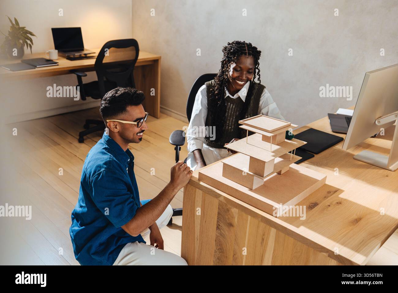 Zwei junge Architekten arbeiten an einem großen Architekturmodell an einem Arbeitsplatz zusammen und zeigen Teamwork, Kreativität und moderne Designansätze in einem Profi Stockfoto
