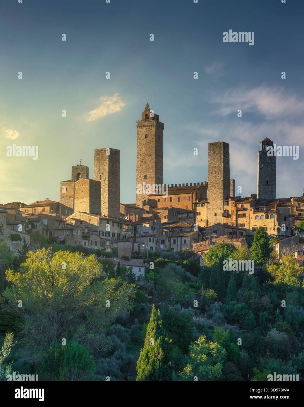 Senkrechter Blick auf die mittelalterlichen Türme von San Gimignano im goldenen Licht des Sonnenuntergangs. Die historische Bergstadt erhebt sich über üppig grüne Hänge Stockfoto