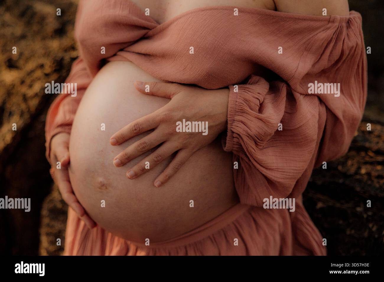 Nahaufnahme einer schwangeren Frau, die ihren Bauch draußen hält Stockfoto