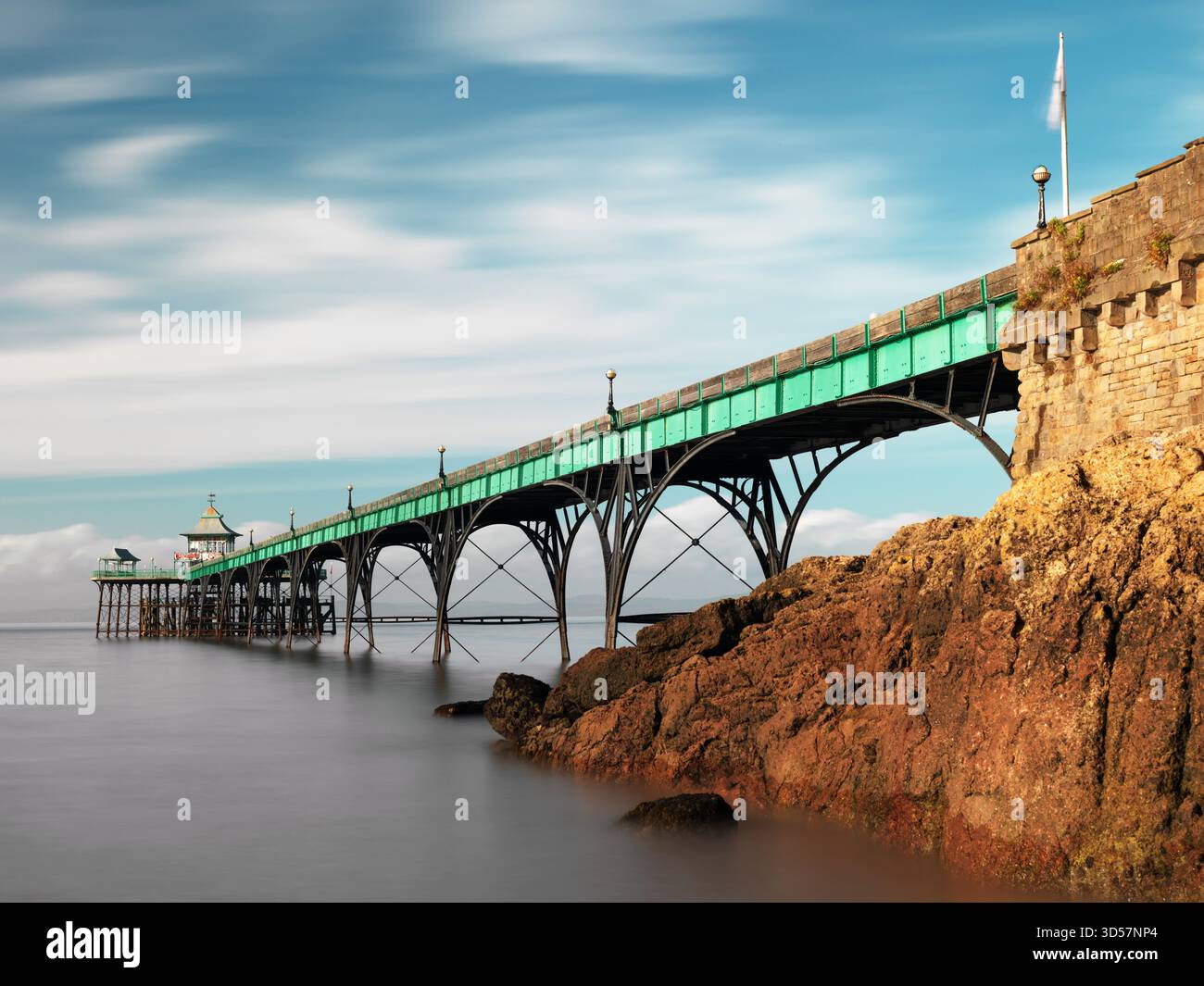 Sehr lange Belichtung. Clevedon Pier mit Felsen in der Sonne - breit Stockfoto