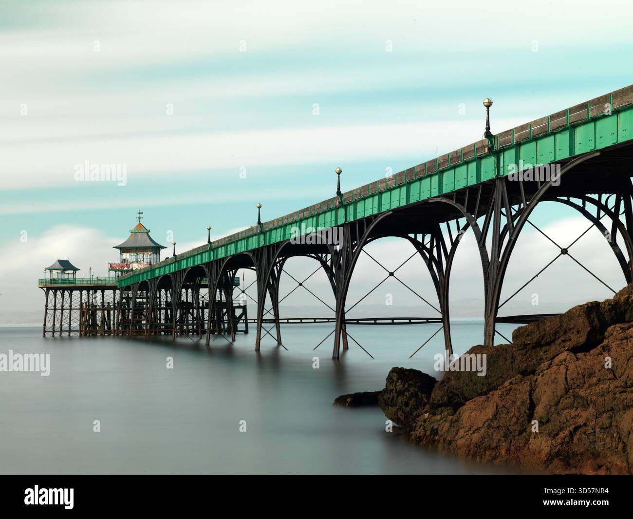Sehr lange Belichtung. Clevedon Pier mit Felsen im Schatten - breit Stockfoto