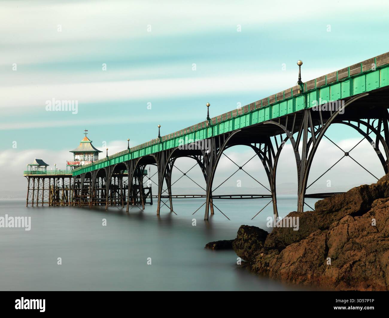 Sehr lange Belichtung. Clevedon Pier mit Felsen in der Sonne - breit Stockfoto
