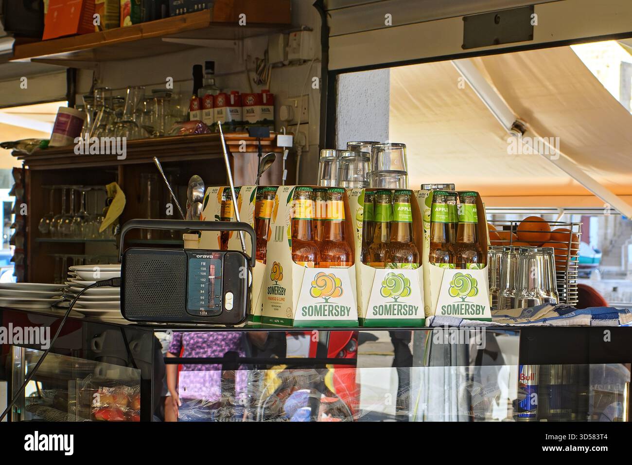 Valletta, Malta - 11.05.2025: Packungen mit Cidre und Glaswaren in Flaschen auf einer Bar aus Glas neben Radio und Café-Ausrüstung Stockfoto