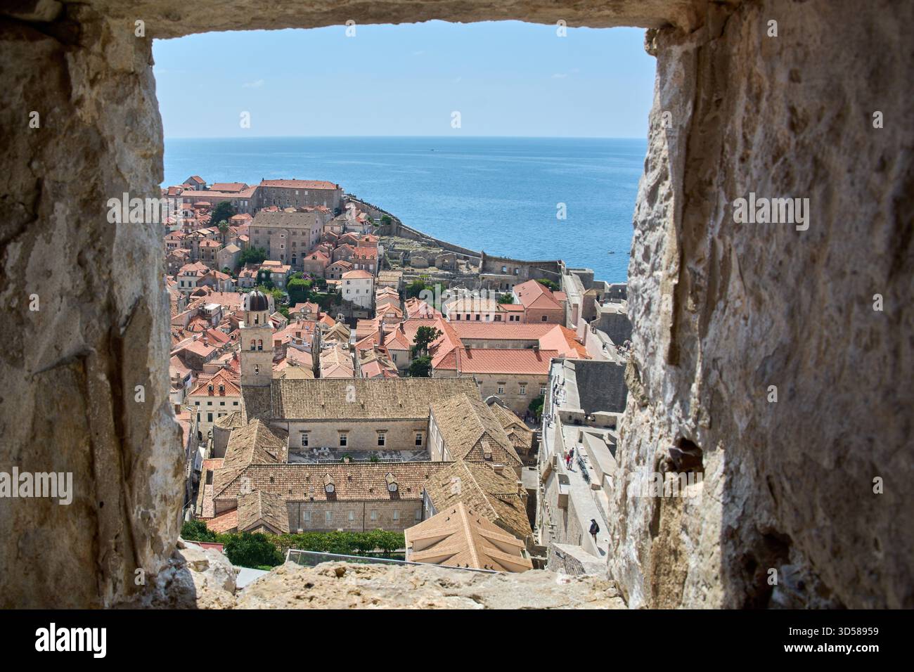 Blick durch eine alte Steinöffnung in den Stadtmauern von Dubrovnik, Kroatien. Die historische UNESCO-Stadt erstreckt sich bis zum blauen Meer. Reise und Ziel Stockfoto