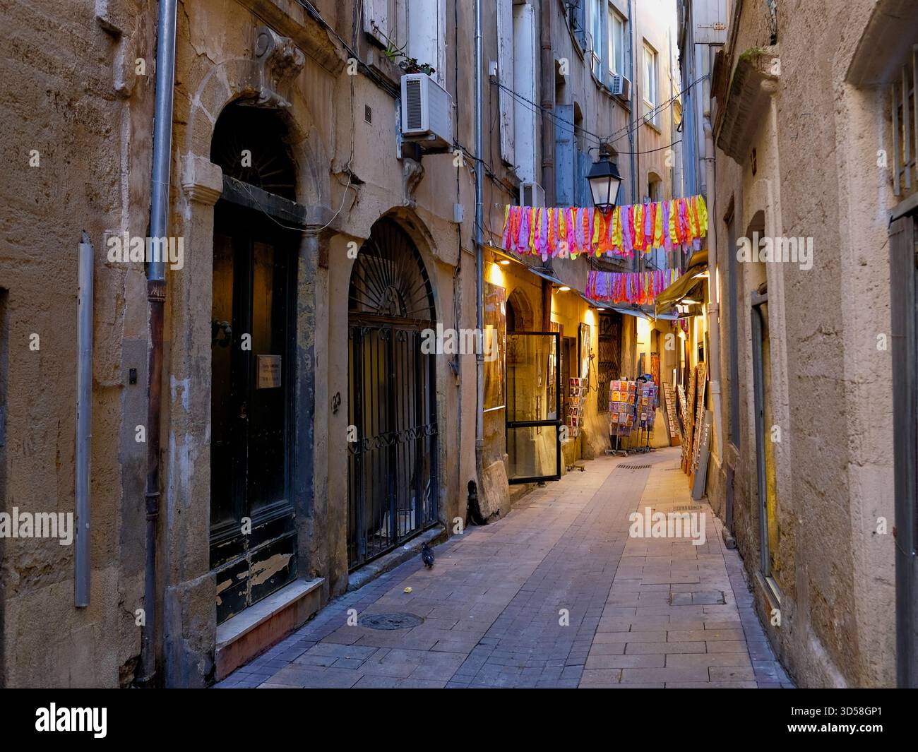 Montpellier Herault France 08.11.25 enge gepflasterte Altstadtallee. Steinhäuser. Bogentüren. Shop für Postkarten. Rote und gelbe Fahnen. Krank Stockfoto