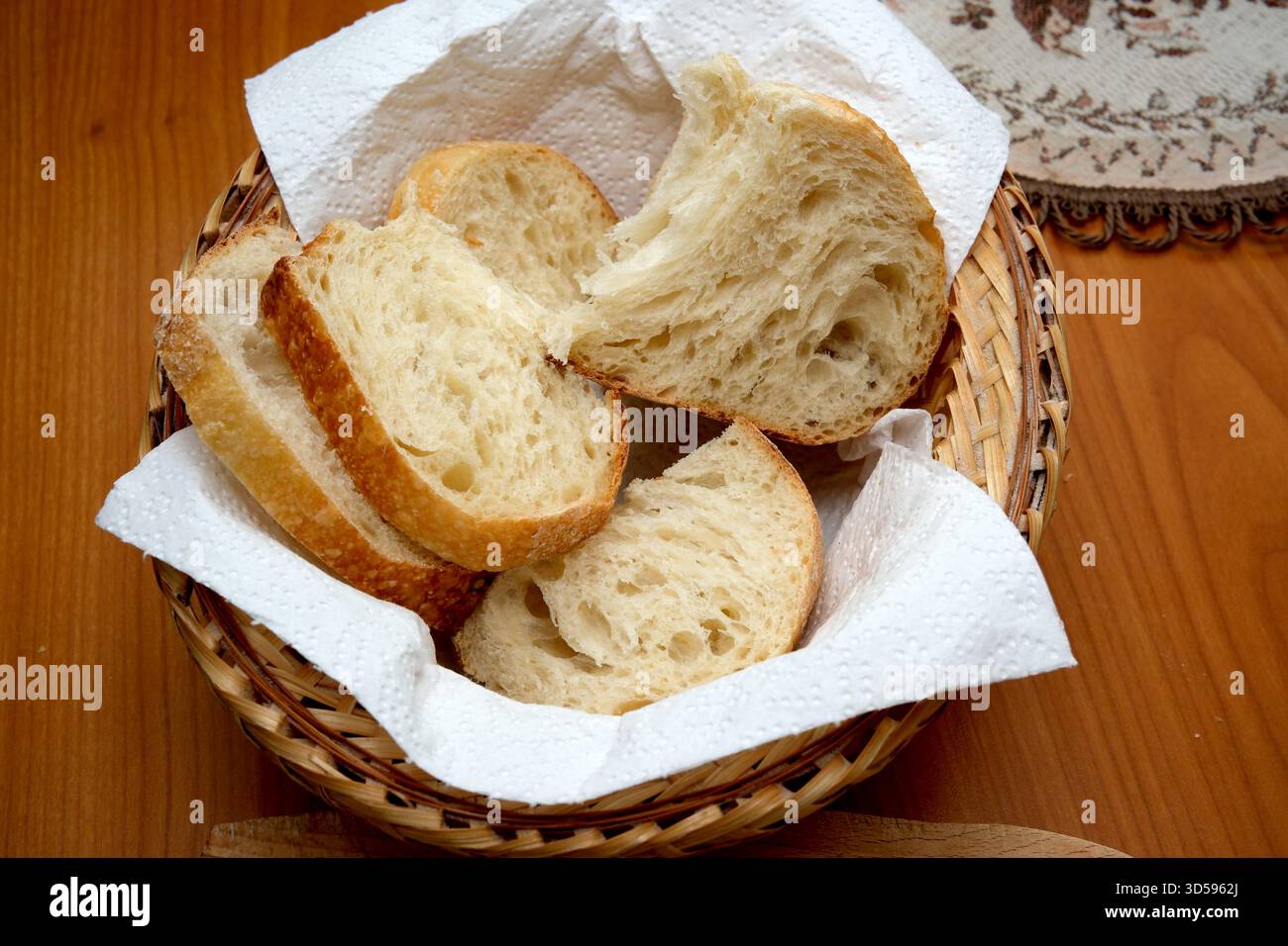 Warme Brotscheiben werden in einem gewebten Korb präsentiert und laden zum Teilen ein. Stockfoto