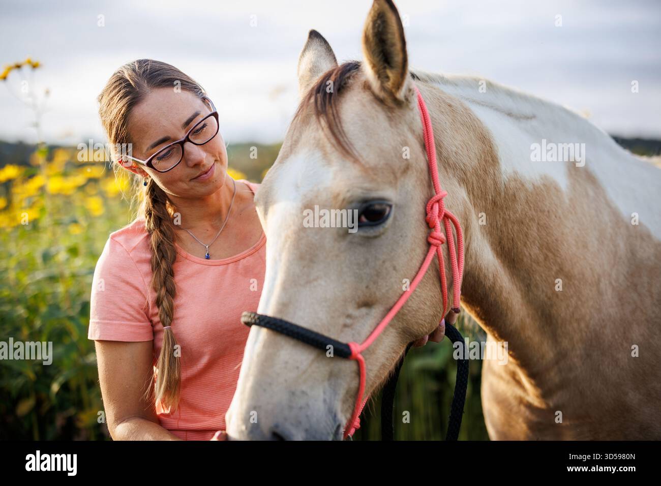 Pferdeassistierte Therapie auf der Tierhaltung. Kaukasierin mit Brille streichelt Therapiepferd im Freien Stockfoto