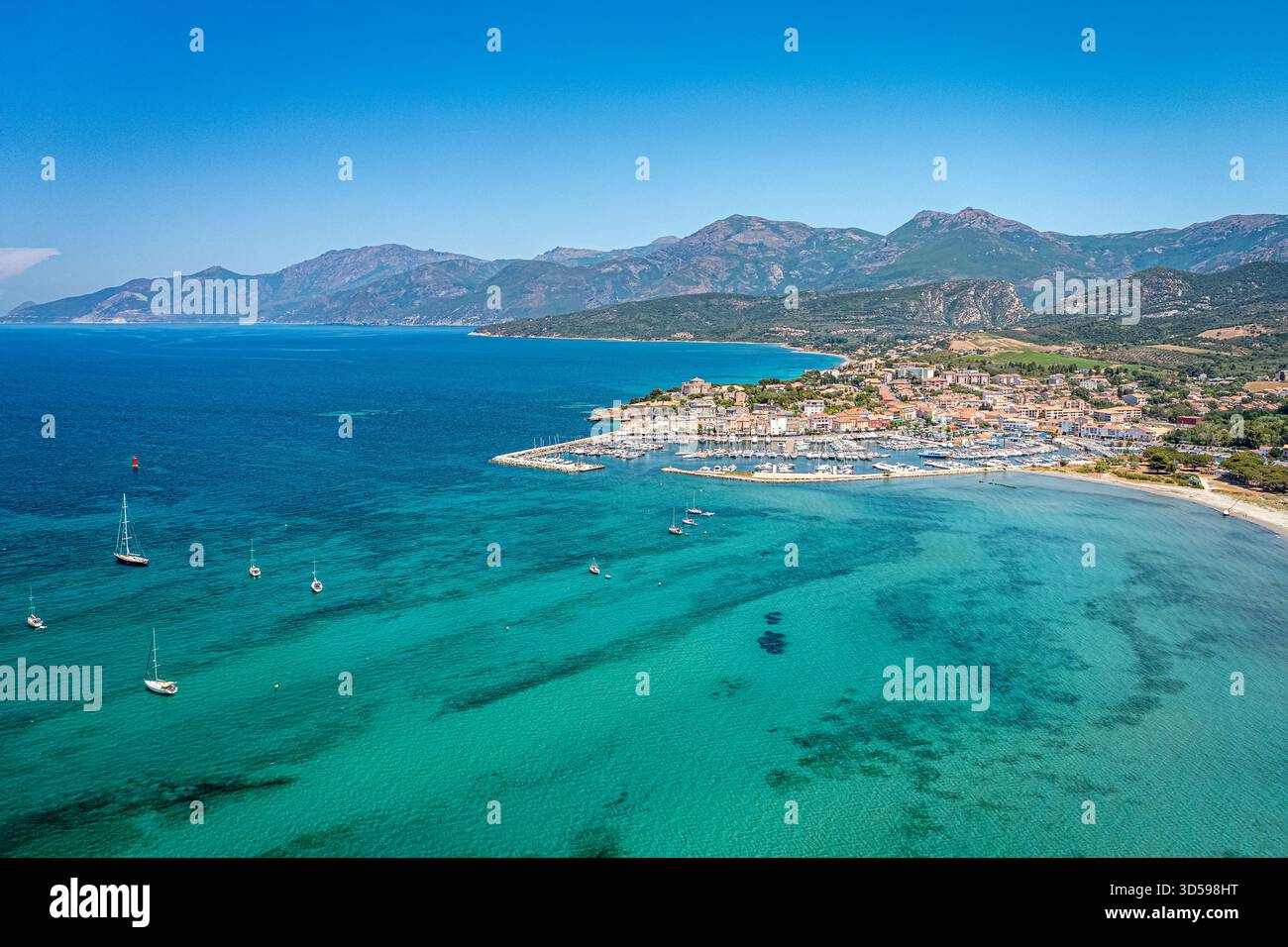 Eine lebendige Küstenstadt an einer Mittelmeerküste, mit einem geschäftigen Yachthafen, Sandstrand und türkisfarbenem Wasser. Korsika, Frankreich Stockfoto