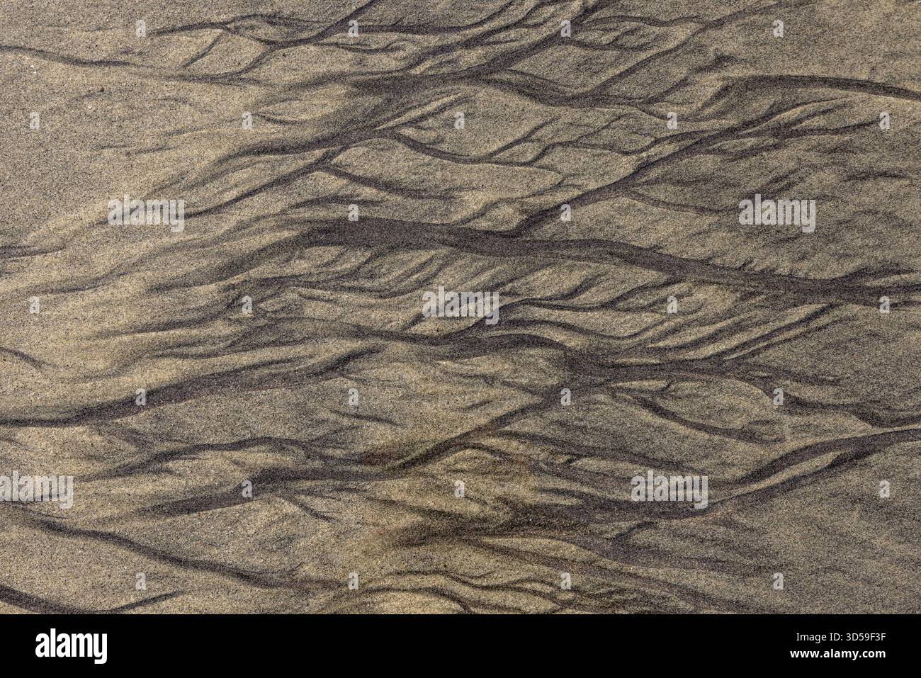 Dunkle Mineralstreifen bilden komplexe natürliche Sandmuster am Pfeiffer Beach, Big Sur, Kalifornien. Stockfoto