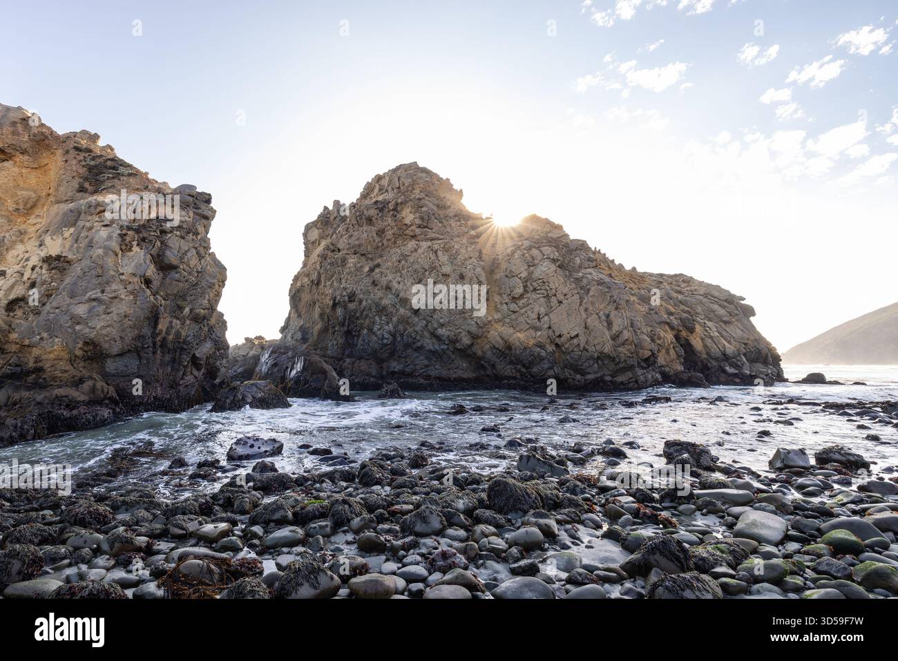 Sonnenlicht beleuchtet zerklüftete Felsformationen über Gezeitenbecken am Pfeiffer Beach, Big Sur, Kalifornien. Stockfoto