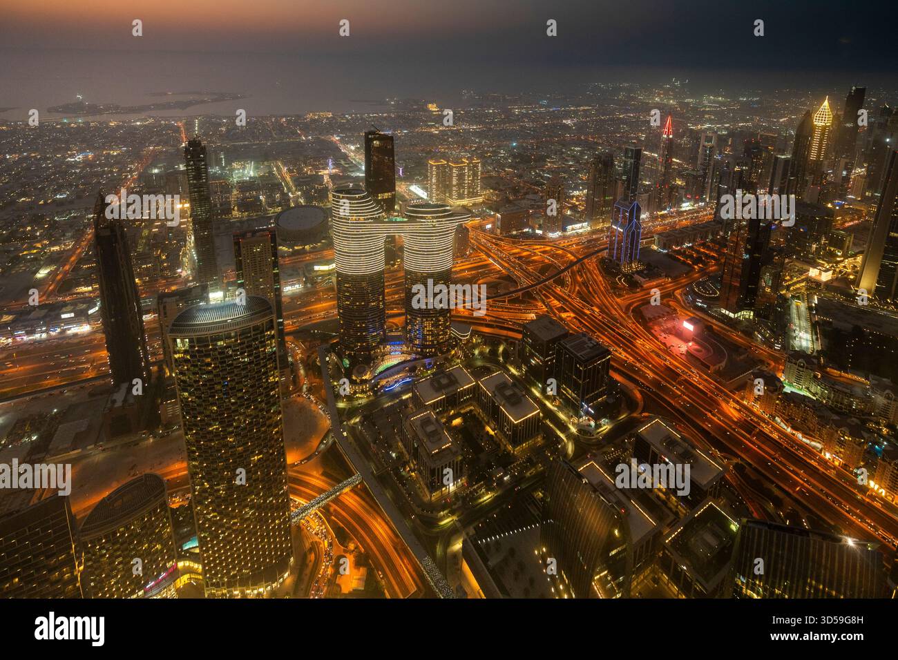 Ein atemberaubender nächtlicher Blick auf Abu Dhabi City von einem der höchsten Türme aus mit glitzernden Wolkenkratzern, beleuchteten Straßen und Reflexionen Stockfoto