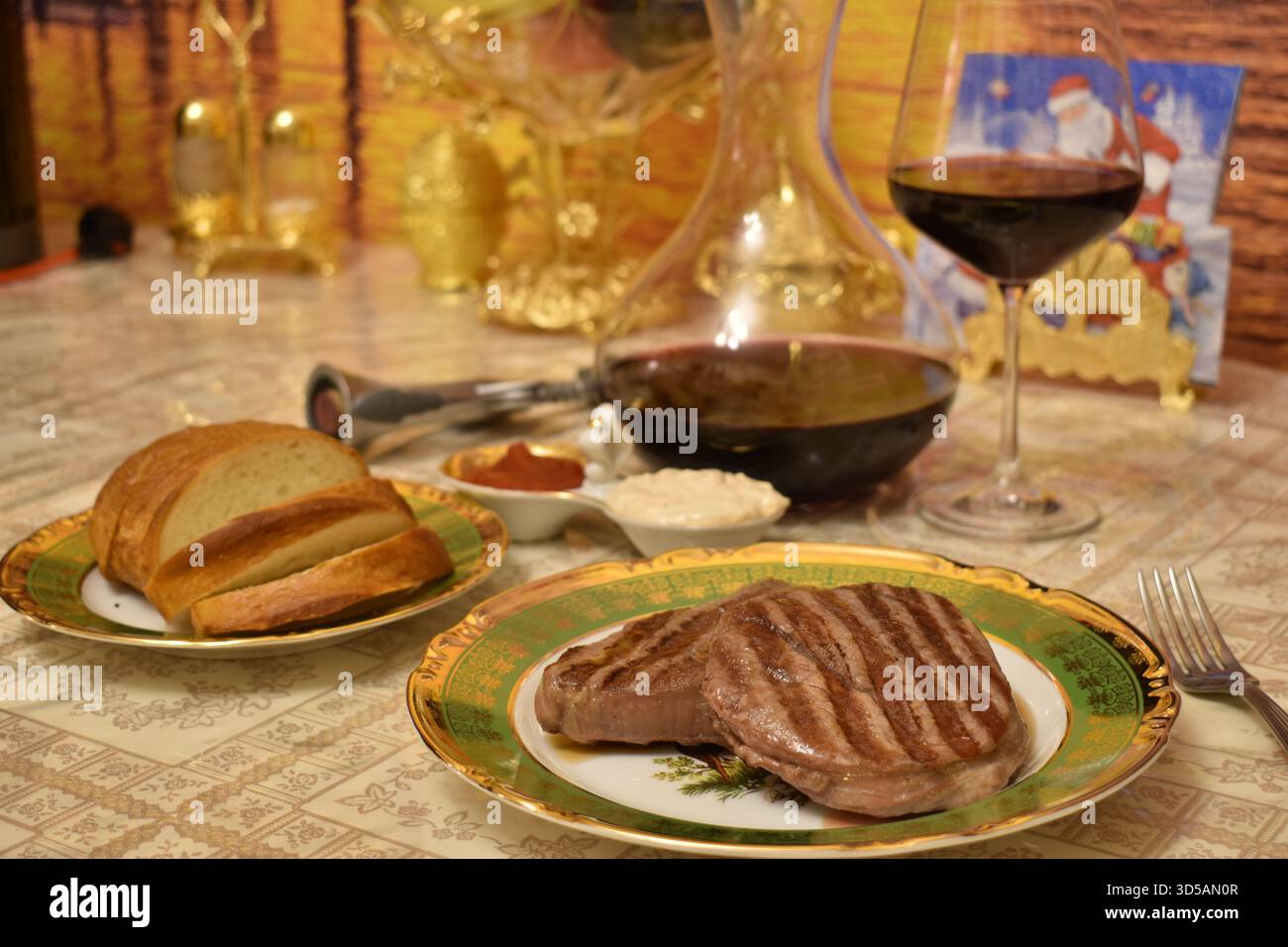 Nahaufnahme eines perfekt gegrillten Steaks, serviert mit einer Karaffe Rotwein und einem gefüllten Glas Stockfoto
