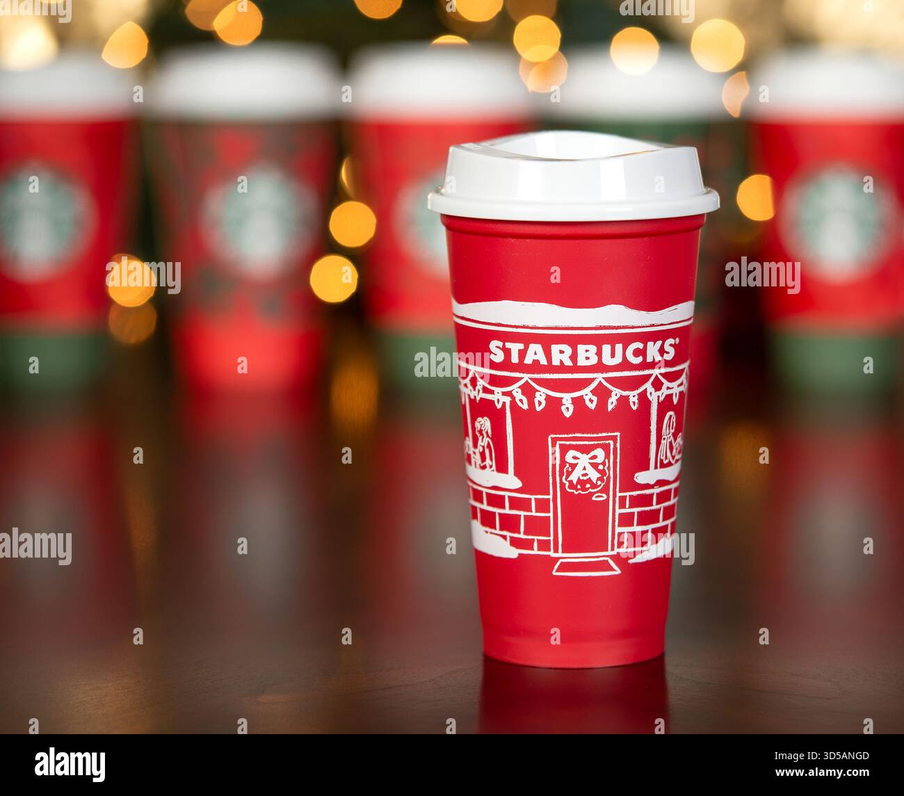 Dallas, Texas - 14. November 2025: Starbucks Kaffeegetränk in der 2025 entworfenen wiederverwendbaren roten Tasse. Einweg-Pappbecher im Hintergrund. Holiday boke Stockfoto