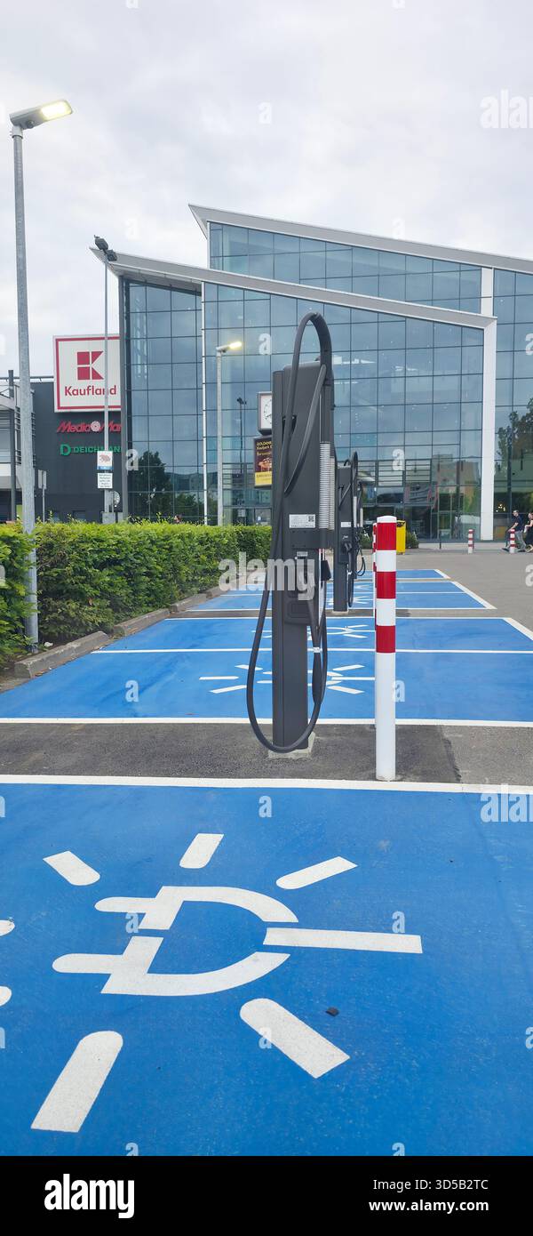 Berlin, Deutschland - 28. Juni 2025: Die Ladestation für Elektrofahrzeuge befindet sich außerhalb eines modernen, grünen Gebäudes. - Smartphone-aufgenommenes Stockfoto