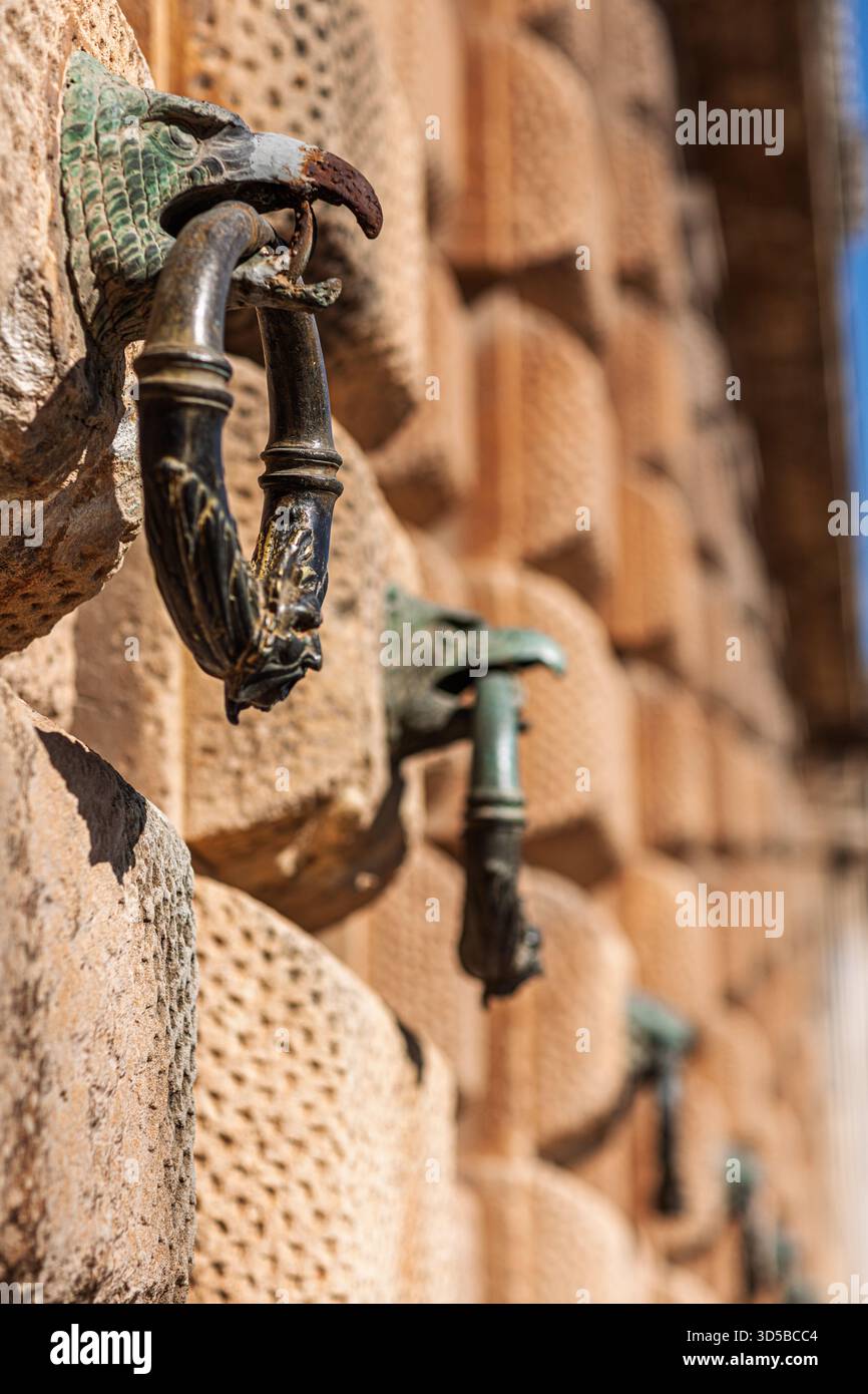 Bronzeringe ruhen auf Adlerkopfhalterungen, die feine Details an der rustikalen Fassade des Palastes Karls V. in Granada, Andalusien, zeigen. Stockfoto