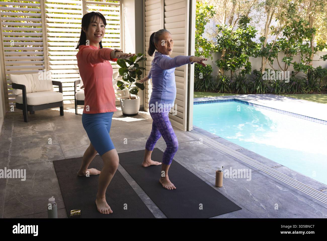 Zwei Frauen üben Yoga am Pool und genießen Sport und Entspannung im Freien Stockfoto