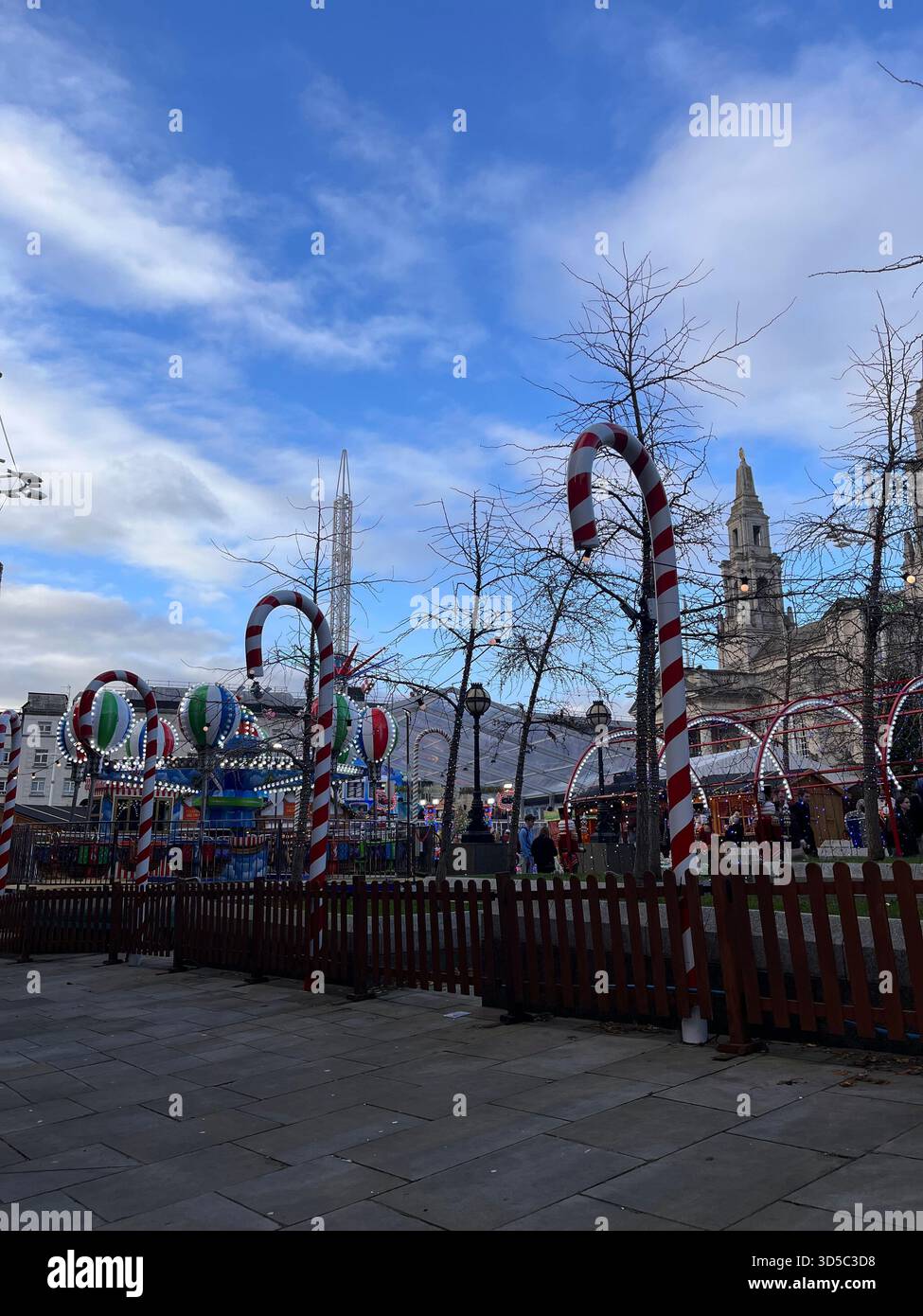 Riesige Zuckerrohrdekorationen und festliche Installationen auf einer Weihnachtsmesse in Leeds, England, mit historischen Gebäuden im Hintergrund und Winterhimmel. Stockfoto