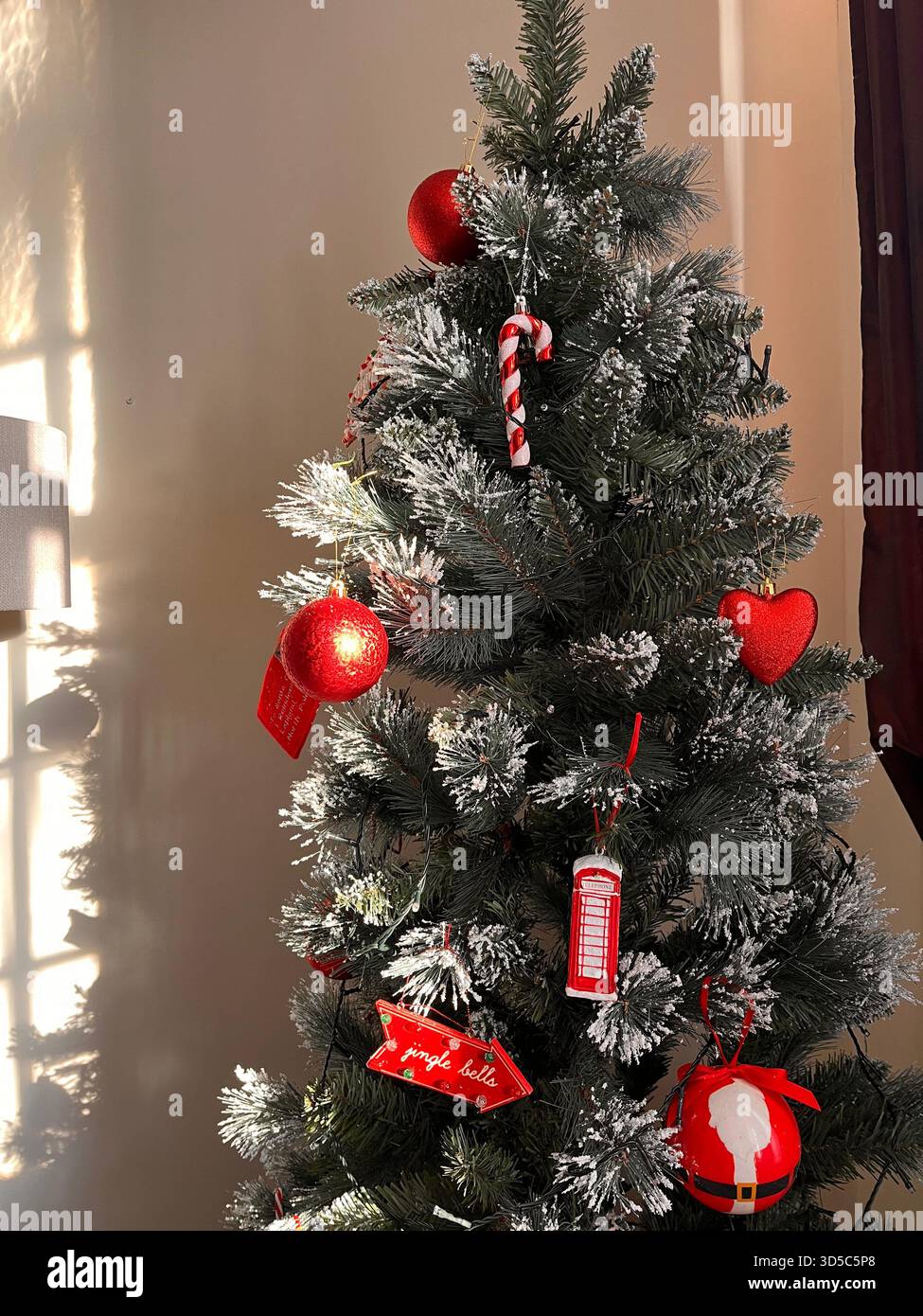 Innenansicht eines kleinen künstlichen Weihnachtsbaums mit roten Ornamenten, Zuckerstangen und festlicher Dekoration in Leeds, England. - Smartphone-aufgenommenes Stockfoto
