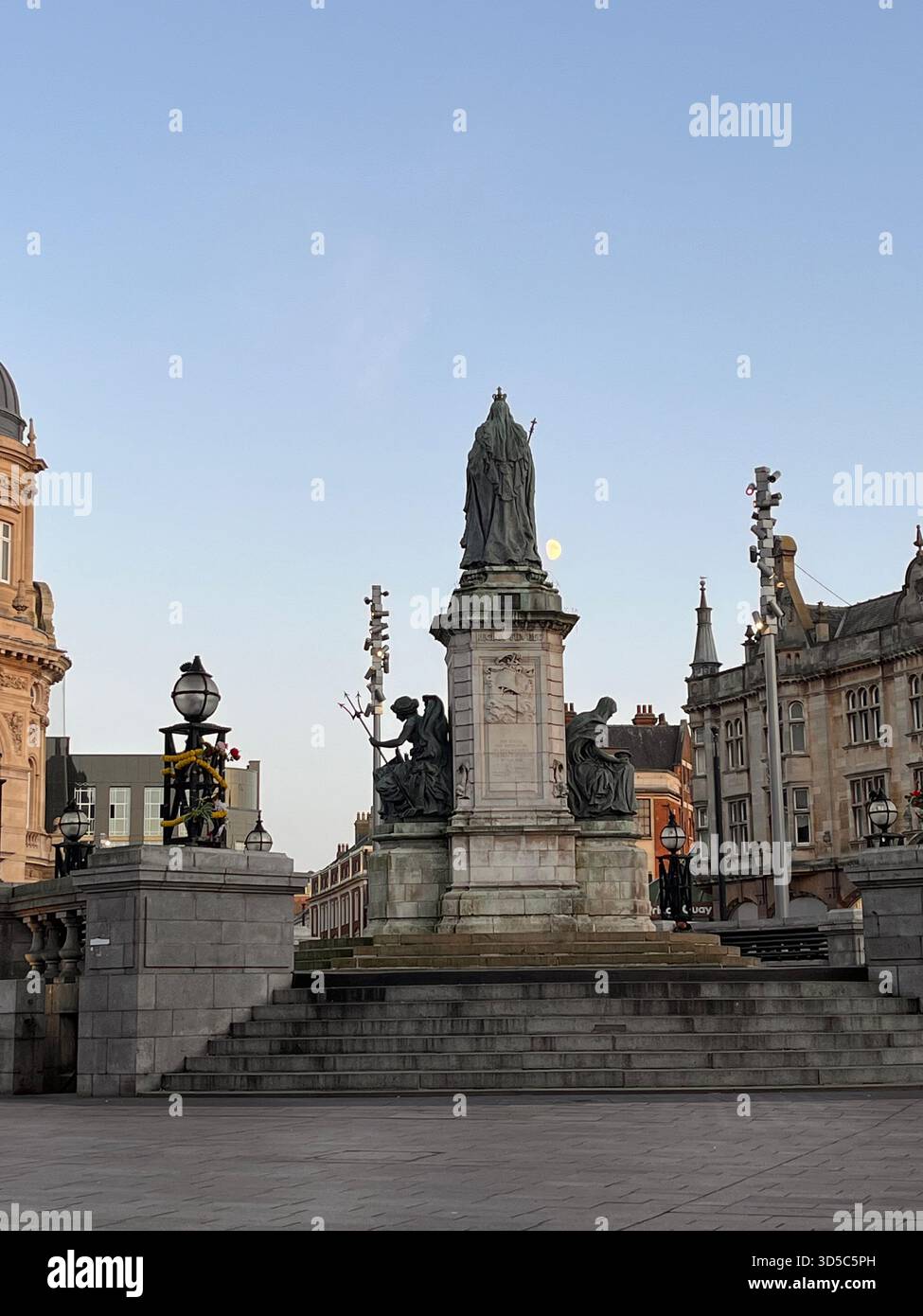 Steindenkmal mit Statue auf einem historischen Stadtplatz im frühen Abendlicht in Hull, England. Städtisches Wahrzeichen umgeben von klassischer Architektur - Smartphone-aufgenommenes Stockfoto