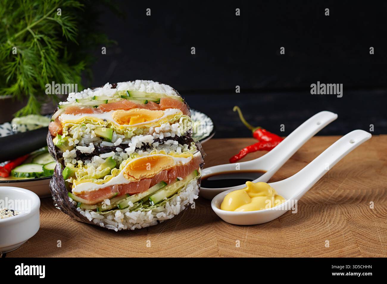 Kreativer Sushi-Burger mit Lachs, Spiegelei, Käse, Gurke und Avocado auf strukturiertem Hintergrund. Stockfoto